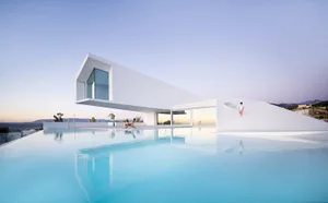 A white minimalist house with a modern architectural design, featuring a large swimming pool and creating a serene, modern at