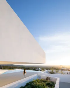 A modern white-rendered concrete architectural structure with a panoramic pool view.