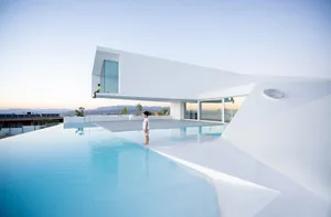 Modern minimalist house with a white-rendered exterior featuring a pool and an open space.