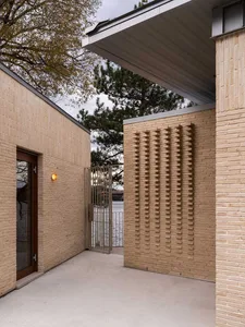 Modern brick exterior of a residential building with a textured wall and a glass door.