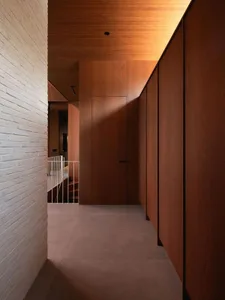 Modern interior corridor with wooden walls and floors, leading to a staircase.