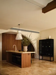 A modern minimalist kitchen featuring wooden cabinetry, marble countertops, and glass displays.
