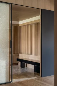 A modern bathroom featuring wooden paneling and a black bench.