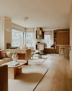 A modern living room featuring wooden furniture and light-colored rugs.