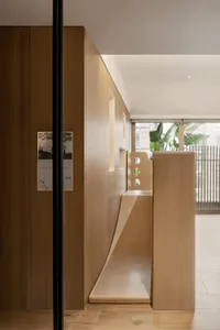 A minimalist children's play area featuring a wooden slide integrated into a wooden wall with cut-out windows.