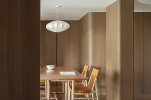 A modern minimalist dining room with wooden chairs and a dining table.