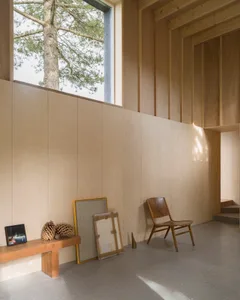 A modern wooden house interior with natural light streaming in through large windows.