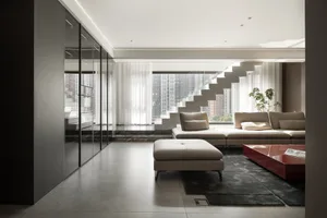 A modern living room featuring concrete walls and floors, with a large white couch and a red coffee table