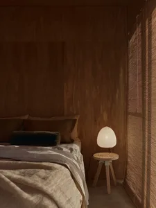 Bedroom features wooden walls and a wooden bedside table with a light lamp.