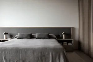 A minimalist bedroom with a gray fabric bedspread and matching pillows.