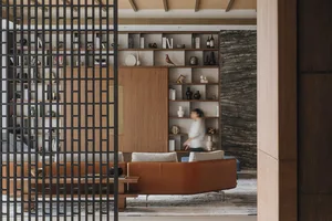 A modern contemporary living room featuring a sleek leather sofa and a wall-mounted bookshelf with various decorative items a