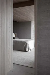 Modern minimalist bedroom with gray walls, white bedding, and concrete floor.