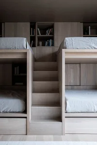 Modern, minimalist bunk beds made of wood with integrated stairs and storage compartments.