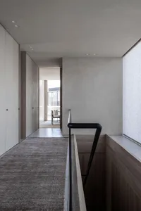 A sleek, modern residential corridor featuring a concrete floor and wood-paneled walls.