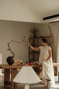 A woman sitting at a wooden table arranging floral decorations.