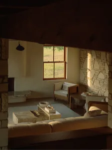 A modern living room with concrete and stone walls, a large window, and minimalist furniture.
