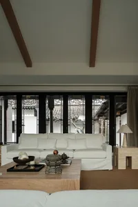 White sofa in a living room with wooden beams on the ceiling and traditional Chinese-style windows, featuring a wooden coffee