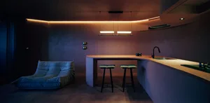 A modern, minimalist residential kitchen with sleek countertops and seating.