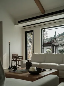 Modern living room featuring a white sofa, wooden coffee table, and large windows overlooking traditional Chinese architectur