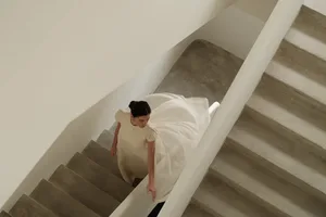 A woman wearing a white dress walking down a set of stairs.