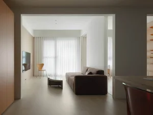 A modern living room featuring neutral-colored furnishings, minimalist design, and large windows allowing natural light to fl