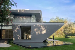 A modern house with concrete exterior and large glass windows.