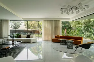 Modern living room with marble flooring, white sofa, and glass ceiling.