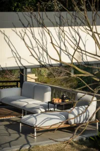 Modern outdoor patio featuring white cushioned lounge furniture and light wooden accents.