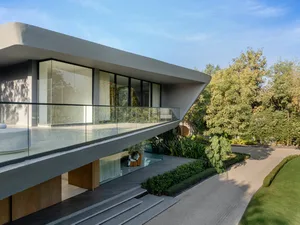 Modern residential home with concrete exterior and large glass windows and doors.
