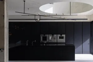 Modern black kitchen with minimalist design and concrete countertops.