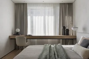 Modern bedroom featuring fabric bedding, a wooden desk, and glass vases.