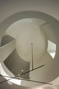 A modern circular ceiling light fixture hanging from a high ceiling.