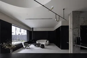 A modern minimalist living room with a white sofa, armchair, and black accents.