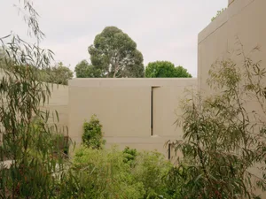 A minimalist architectural design featuring a modern exterior with concrete walls and greenery.