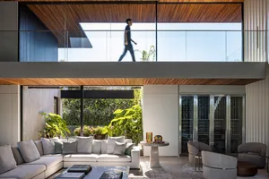 Modern living room with a white sectional sofa, glass coffee table, and green plants
