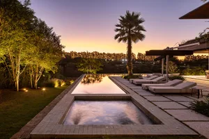 Modern poolside area with concrete cubes and lounge chairs at sunset.