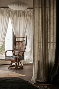A stylish living room with a rattan chair and fabric curtains, featuring a modern design aesthetic.