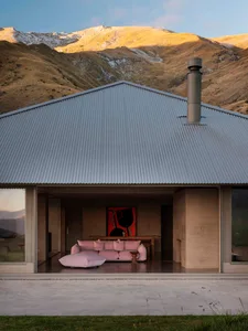 A minimalist interior design featuring a pink sectional sofa with pink cushions and a metal roof.