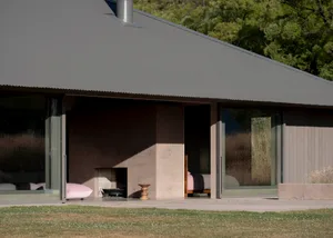 A modern minimalist house featuring a concrete exterior with large glass windows and a flat roof.