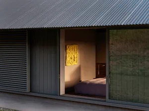 Modern bedroom featuring a metal-clad wall and large windows.