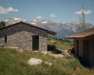 Modern residential architecture featuring stone exterior against a mountainous backdrop.