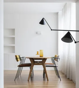 Minimalist dining room with wooden furniture and modern lighting fixtures.