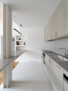 Modern minimalist kitchen with white walls and concrete countertops.