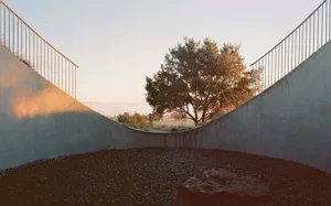 A minimalist, modern architectural space with concrete walls and a gravel floor.