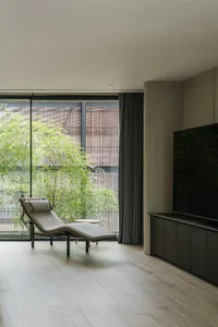 A modern living room with a lounge chair, large window, and wooden flooring.