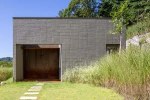A modern minimalist home with a concrete exterior and a simple walkway leading to the entrance.