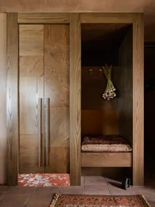 A modern wardrobe or storage nook made of oak wood, featuring a cushioned seating area and decorative onion bunch.