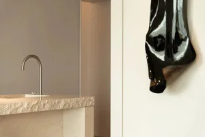 A minimalist bathroom with a sink made of natural stone and a metallic faucet.