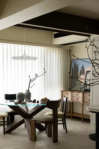A modern minimalist dining room with glass table, wooden chairs, minimalist decor, and artistic painting.