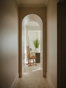 A minimalist corridor with an architectural arch, featuring wooden elements and plants.